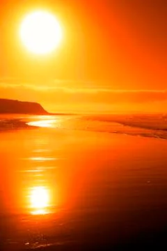 Distant cliffs on a sunset beach Stock Photos