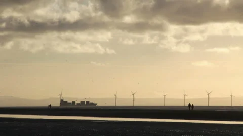 Distant container ship passing Liverpool Bay wind turbines, backlit. Stock Footage 35790297