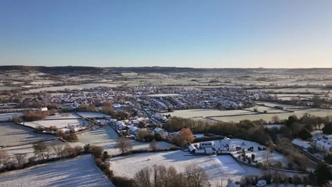 Distant Drone pan over Small snow covered UK Village at sunrise in 4K Видео 329968217