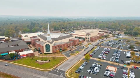 Distant drone shot of a mega church building that has a full parking lot Stock Footage 241497501