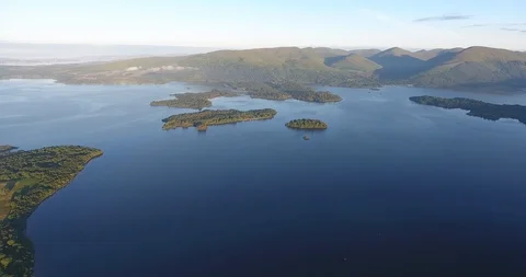 Distant Drone Shot of Scottish Lake Featuring a Large Green Island 動画素材 97571732