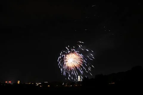 Distant flash of a firework explosion at night against a black sky Stock Photos
