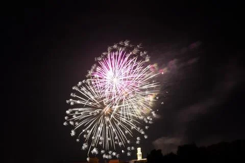 Distant flash of a firework explosion at night against a black sky Stock Photos