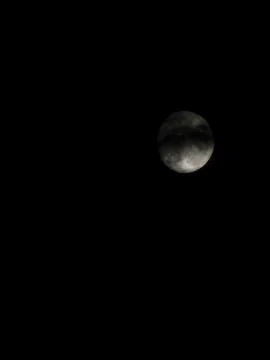 Distant full moon behind night clouds. Stock Photos