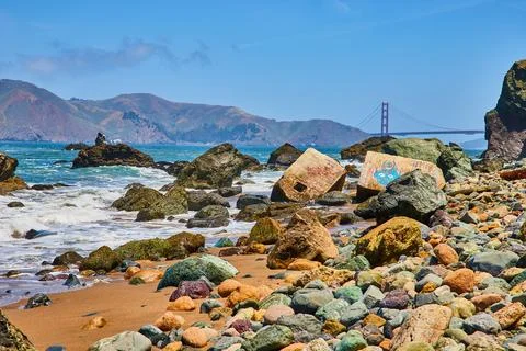 Distant Golden Gate Bridge with close view of colorful pebble strewn shore with Stock Photos