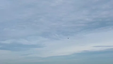 A distant helicopter flies across a cloudy blue sky, framed in a minimalist. Vidéo 310909036