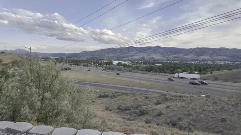 Distant hills lie under a cloudy sky overlooking highway into Pocatello Valley Stock Footage 340430157