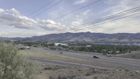 Distant hills stretch beneath a cloudy sky overlooking highway outside Pocatello Stock Footage 340430210