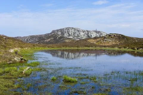 A distant Holyhead mountain is reflected in a shallow pond on Anglesey, Wales Stock Photos