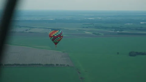 Distant hot air balloon over farmland patterns at dusk Stock Footage 317159601