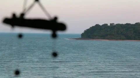 Distant island at the sea with wind chimes swinging in the foreground Stock Footage 51034599
