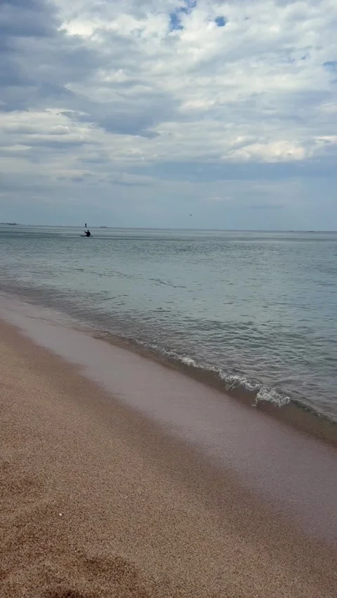 Distant kayaker paddling along calm sea near sandy beach. Peaceful coastal Stock Footage 337412038