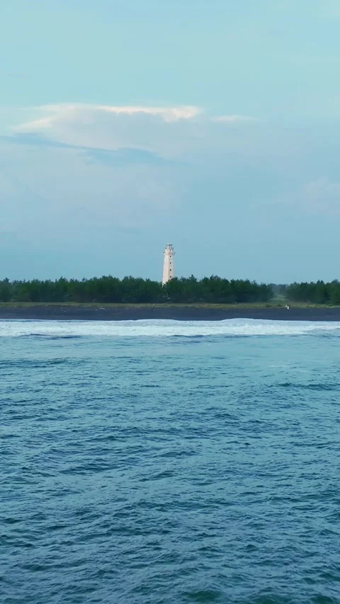 Distant lighthouse across blue coastal water Vídeo Stock 335432910