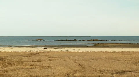Distant lighthouse and rock formations on a beachfront Stock Footage 49935016