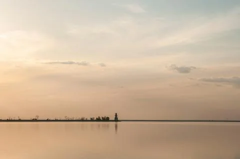 Distant lighthouse on the dam at sunset Stock Photos