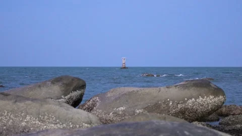 Distant lighthouse flashing red light at with huge stones coastline in the Stock Footage 314973918