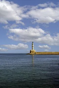 Distant Lighthouse on Harbour wall with blue sky and fluffy white clouds Foto stock