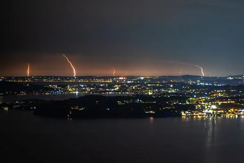 Distant lightning bolts strike beyond the calm waters of Lake Garda in Italy. Stock Photos