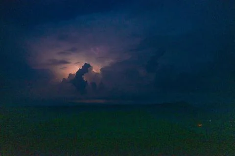 Distant lightning illuminates storm clouds at night Stock Photos