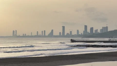 Distant Limassol seafront silhouette emerges through coastal haze over calm Stock Footage 334319893