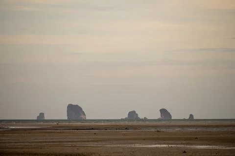 Distant limestone islands across low tide beach Thailand Stock Photos