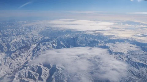 Distant mountain range against blue sky from airplane window Stock Footage 129044704