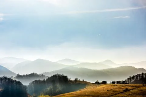 Distant mountain range and thin layer of clouds on the valleys Stock Photos