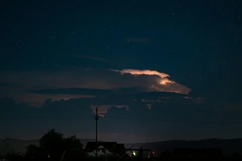 Distant night lightning storm over small rural village and distant hills. Fotos Stock