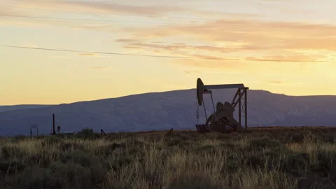 Distant oil pump operates in vast oil field during summer sunrise, Vernal, Utah Stock Footage 248879913
