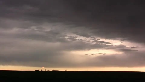 Distant oil well flare w dark storm clouds above Stock Footage 145443353