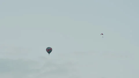 Distant paraglider and hot air balloon drifting across sky Stock Footage 317167616