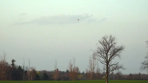 Distant Paraglider Flying Over Rural Farm Field at Sunset 库存影片 345007128