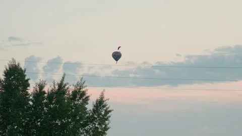 Distant paraglider pilot and hot air balloon drifting across dusk sky Видео 317189236