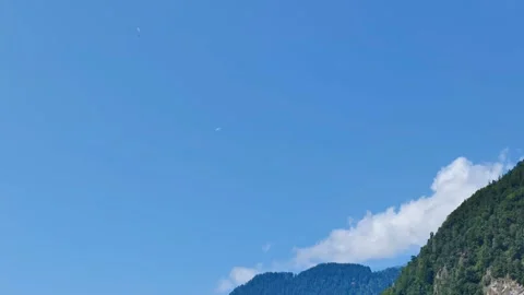 Distant paragliders flying high in clear blue sky over scenic mountains in .. Vidéo 348369982