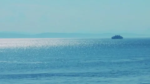 Distant passenger ferry on shimmering blue ocean under clear sky, copy space Видео 331276955