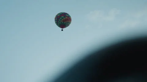 Distant patchwork hot air balloon ascending over field at dawn Stock Footage 317165476