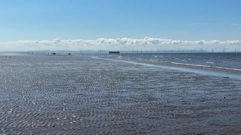 Distant people on the beach ship sailing past offshore wind farm Vídeos de archivo 246543888