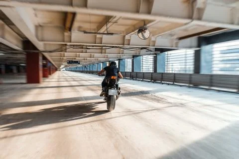 Distant plan of biker riding motorcycle at parking. Urban background. Stock Photos