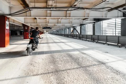 Distant plan of biker riding motorcycle at parking. Urban background. Stock Photos