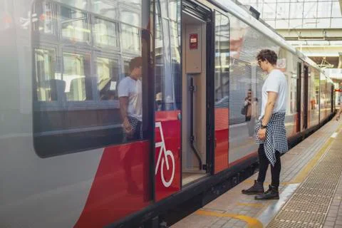 Distant plan of young attractive man looking at arrived train in metro station. Stock Photos