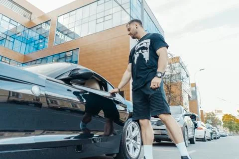 Distant plan of young attractive man getting out of the black car. Stock Photos