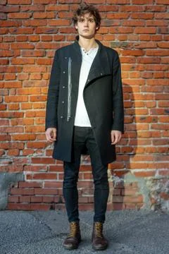 Distant plan of young attractive man standing on red brick background. Stock Photos