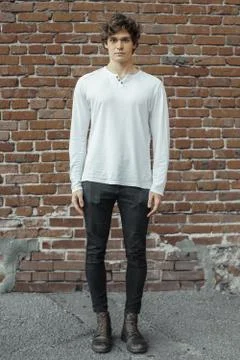 Distant plan of young attractive man standing on red brick background. Stock Photos