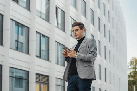 Distant plan of young businessman talking by mobile phone next to skyscraper. Stock Photos