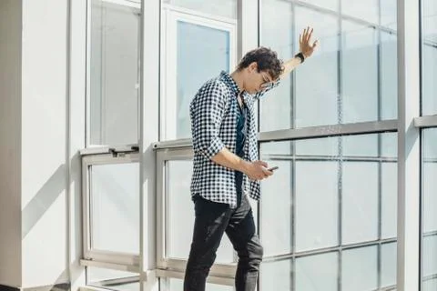 Distant plan of young man looking at mobile phone screen at metro station. Stock Photos