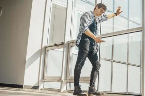 Distant plan of young man looking at mobile phone screen at metro station. Stock Photos