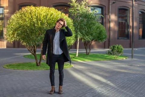 Distant plan of young man passing through red bricked buildings and green trees. Stock Photos