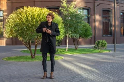 Distant plan of young man passing through red bricked buildings and green trees. Stock Photos