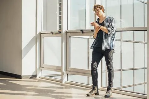 Distant plan of young man standing next to big windows at metro station. Stock Photos