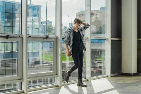 Distant plan of young man standing next to big windows at metro station. Stock Photos